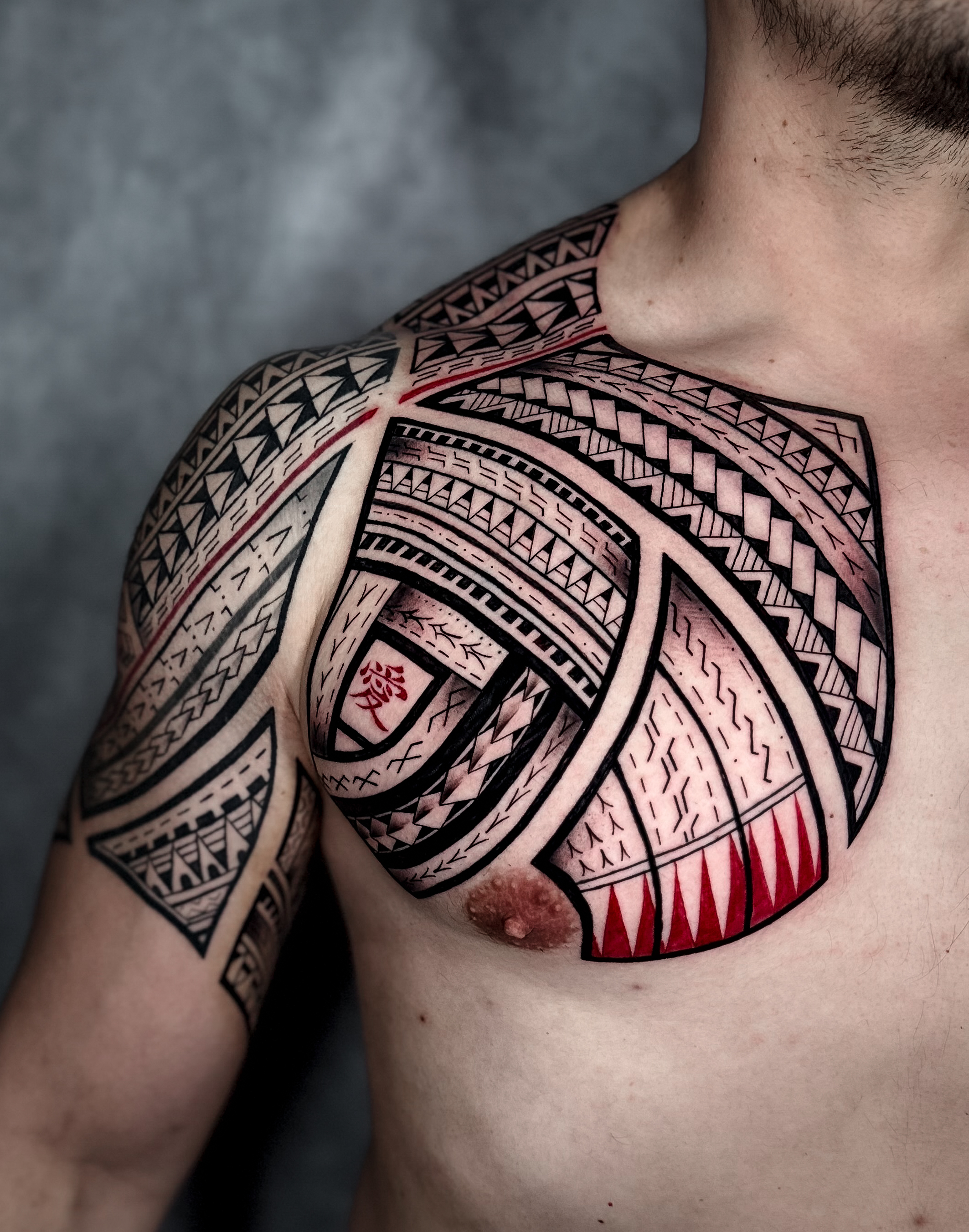 half sleeve and chest tattooed with Polynesian tribal fusing red and black