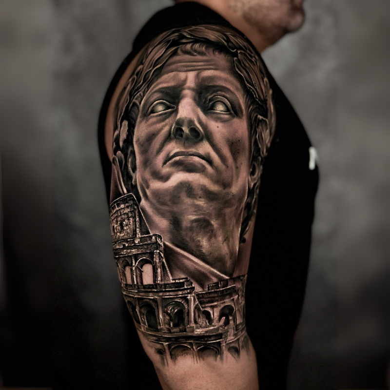 Black & Grey realism featuring a Roman bust and the Colosseum, symbolizing the grandeur of ancient Rome.